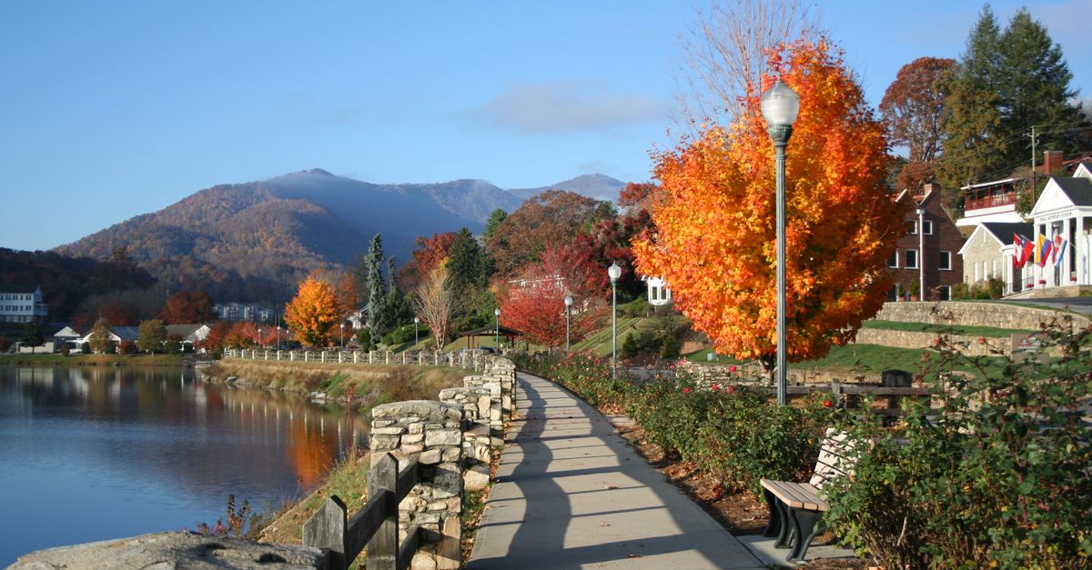 Stunning autumn view of Lake Junaluska with vibrant foliage and mountains in the background.