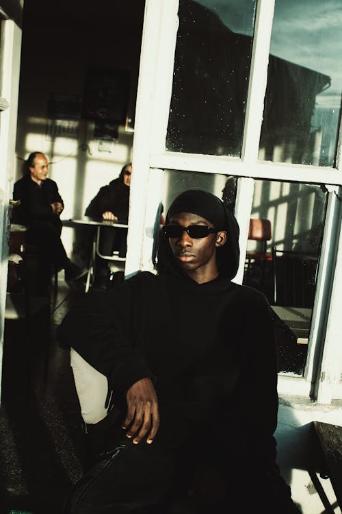 Man Sitting in Black Clothes and Sunglasses