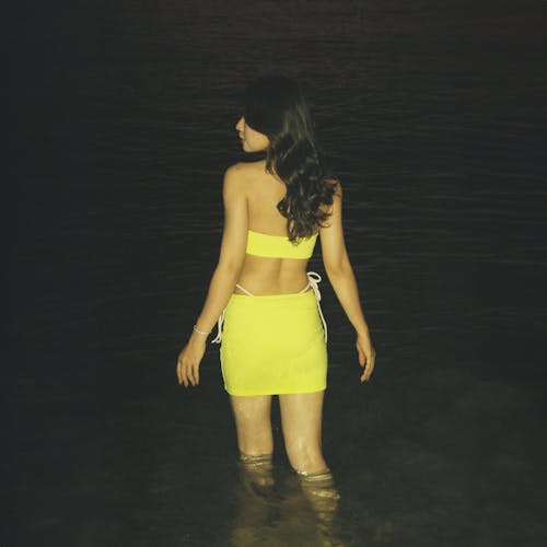 Free A woman in a yellow dress standing in the water Stock Photo