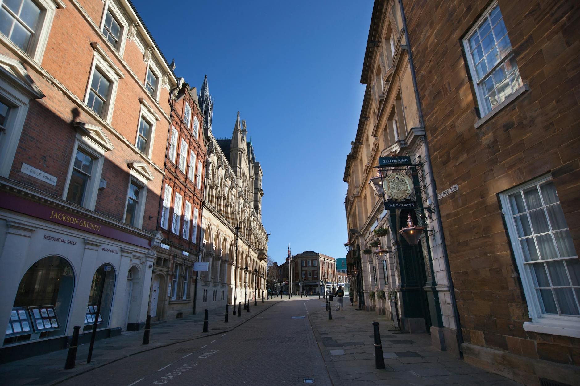 Charming street view in Northampton, UK, showcasing historic architecture and a clear blue sky.