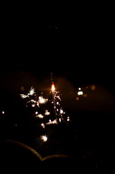 A vibrant sparkler emitting sparks and light against a dark night background.