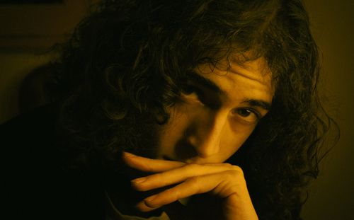Free Introspective close-up portrait of a man with curly hair in dramatic lighting. Stock Photo