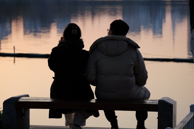 Back View Of Couple Sitting By Lake