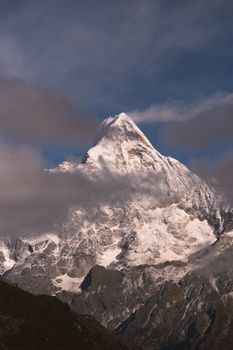 Breathtaking view of snowcapped Mount Siguniang piercing through clouds, capturing scenic beauty.