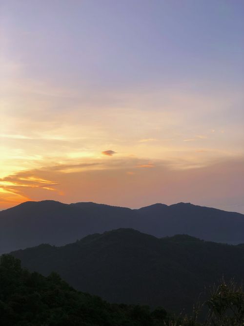 Free A peaceful mountain scene at dusk with a vibrant sky and distant peaks. Stock Photo