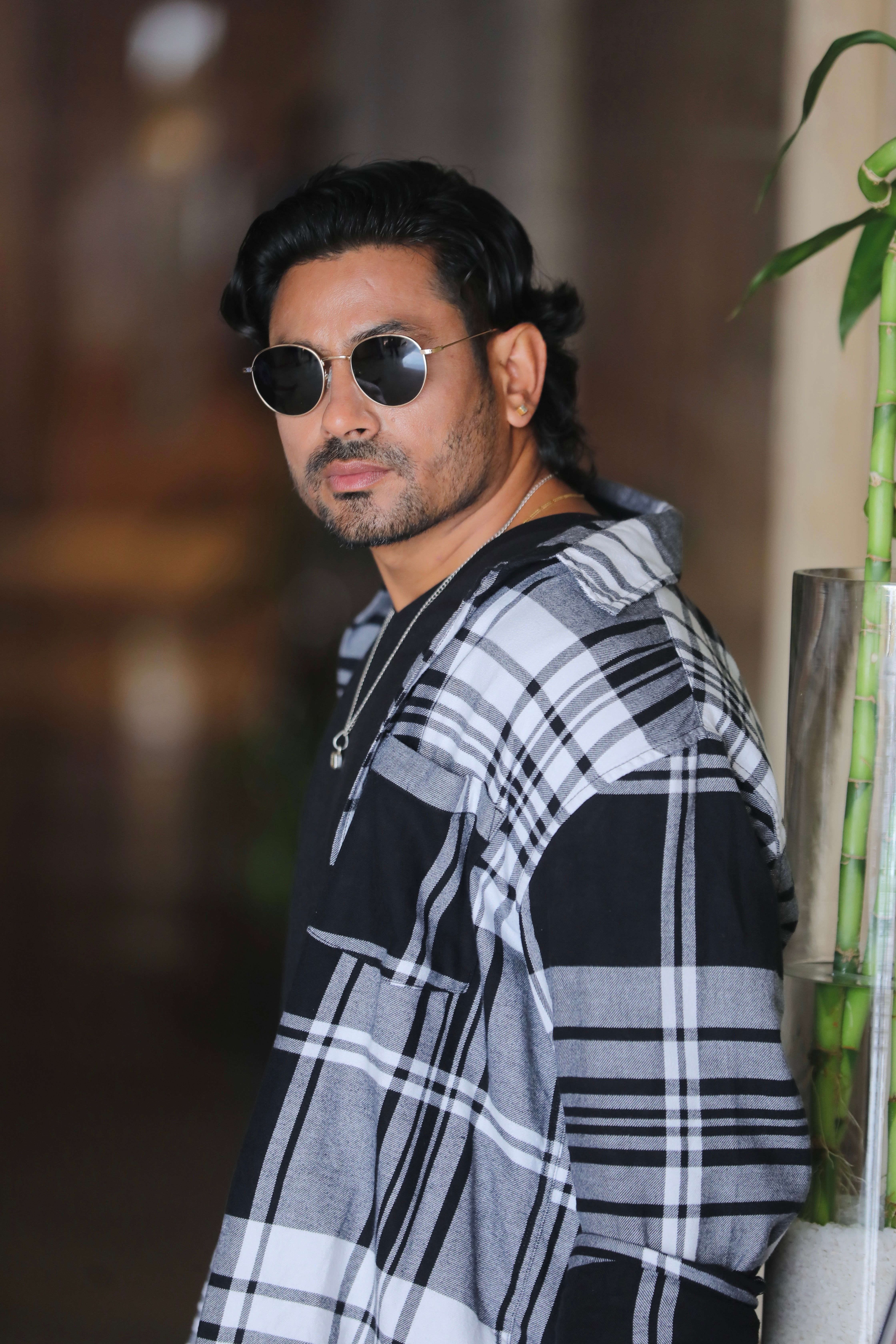 Chic portrait of a fashionable man in round sunglasses and checkered shirt, Jaipur, India.
