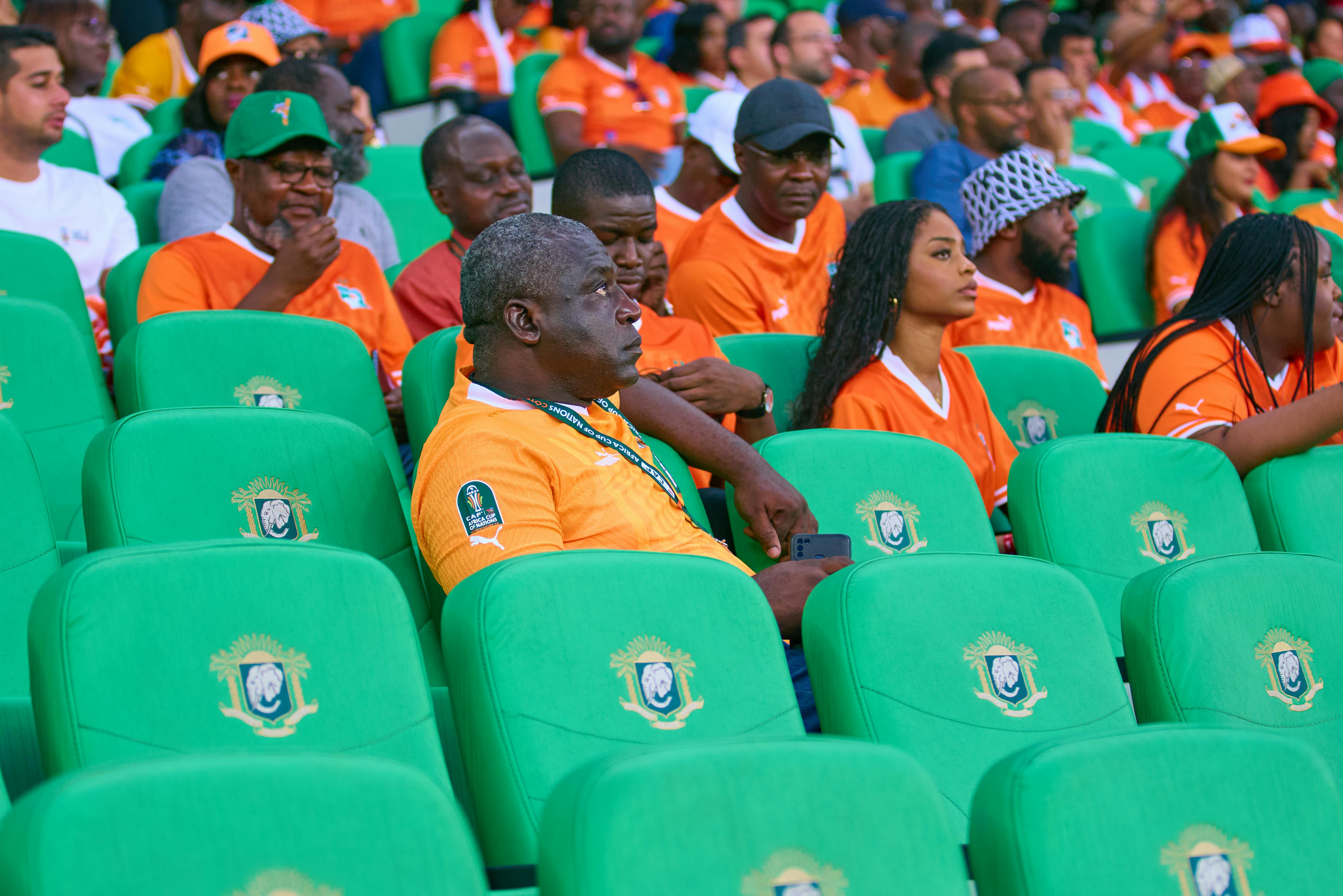 Excited spectators in orange jerseys filling stadium seats creating a vibrant scene.