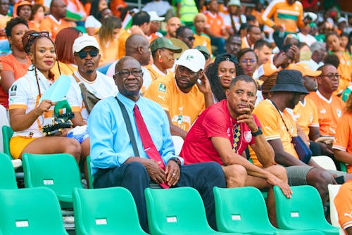 Sport Fans in Orange Shirts Sitting in Stadium Chairs