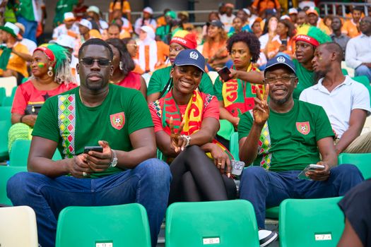 Fans at a soccer stadium showing enthusiasm and v-signs, enjoying the live game.