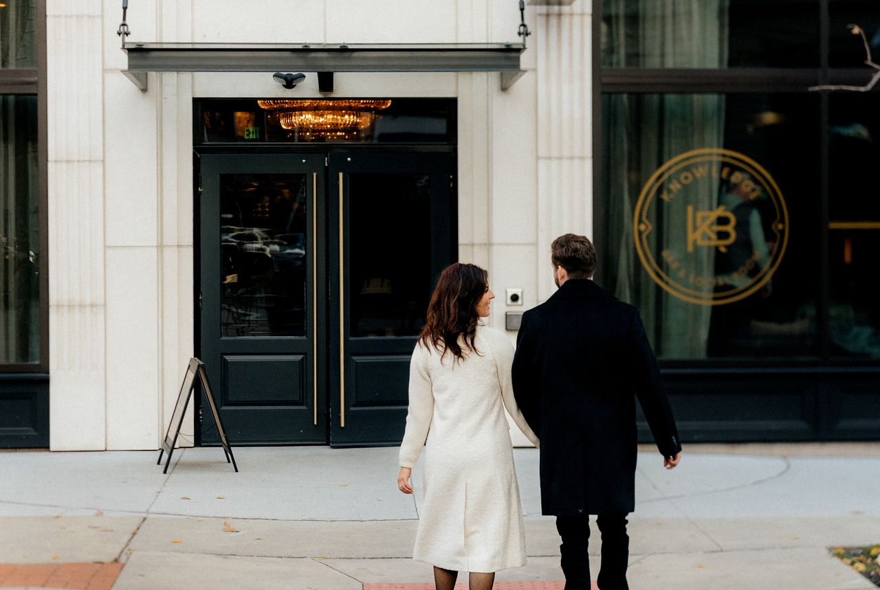 stylish couple in covington ky walking towards a chic building entranc