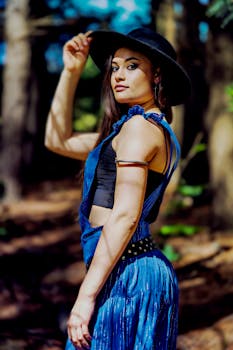 夏季，一位时尚女士穿着蓝色连衣裙、戴着帽子，在户外优雅地摆姿势