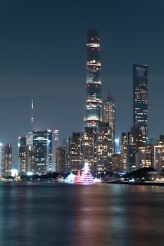 Stunning night shot of Shanghai's iconic skyscrapers reflected on waterfront, capturing urban elegance.