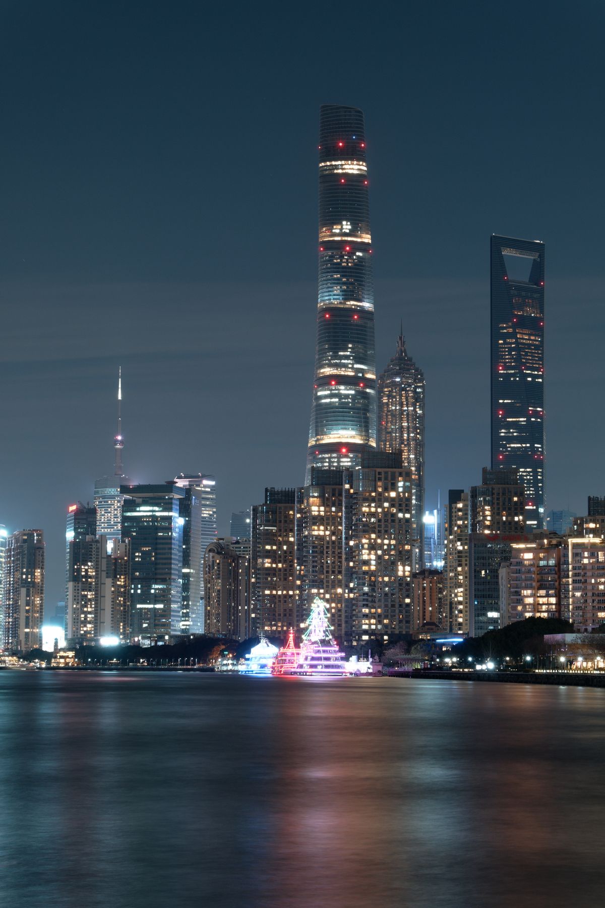 Os arranha-céus de Pudong, em Xangai, refletidos no rio à noite