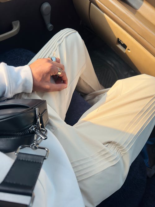 Person with Beige Pants and Black Bag Sitting in a Car