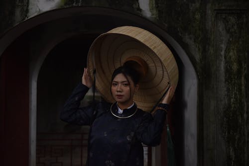 Woman Holding Wide Straw Hat over Head