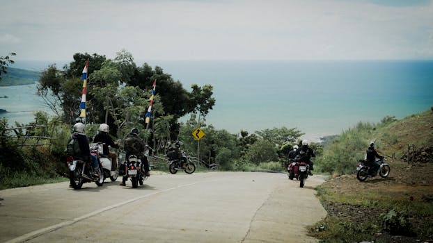 Group of motorcyclists riding along a scenic coastal road with sea view.