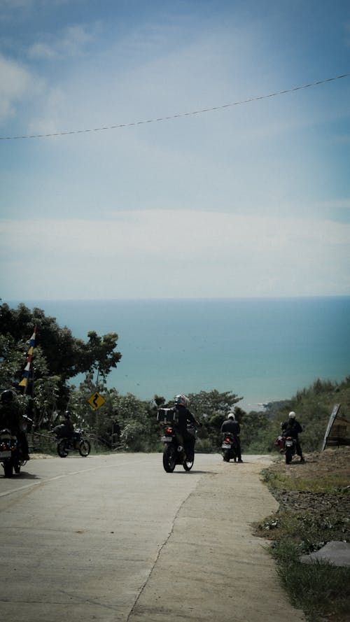 Back View of People on Motorbikes on Road on Coast