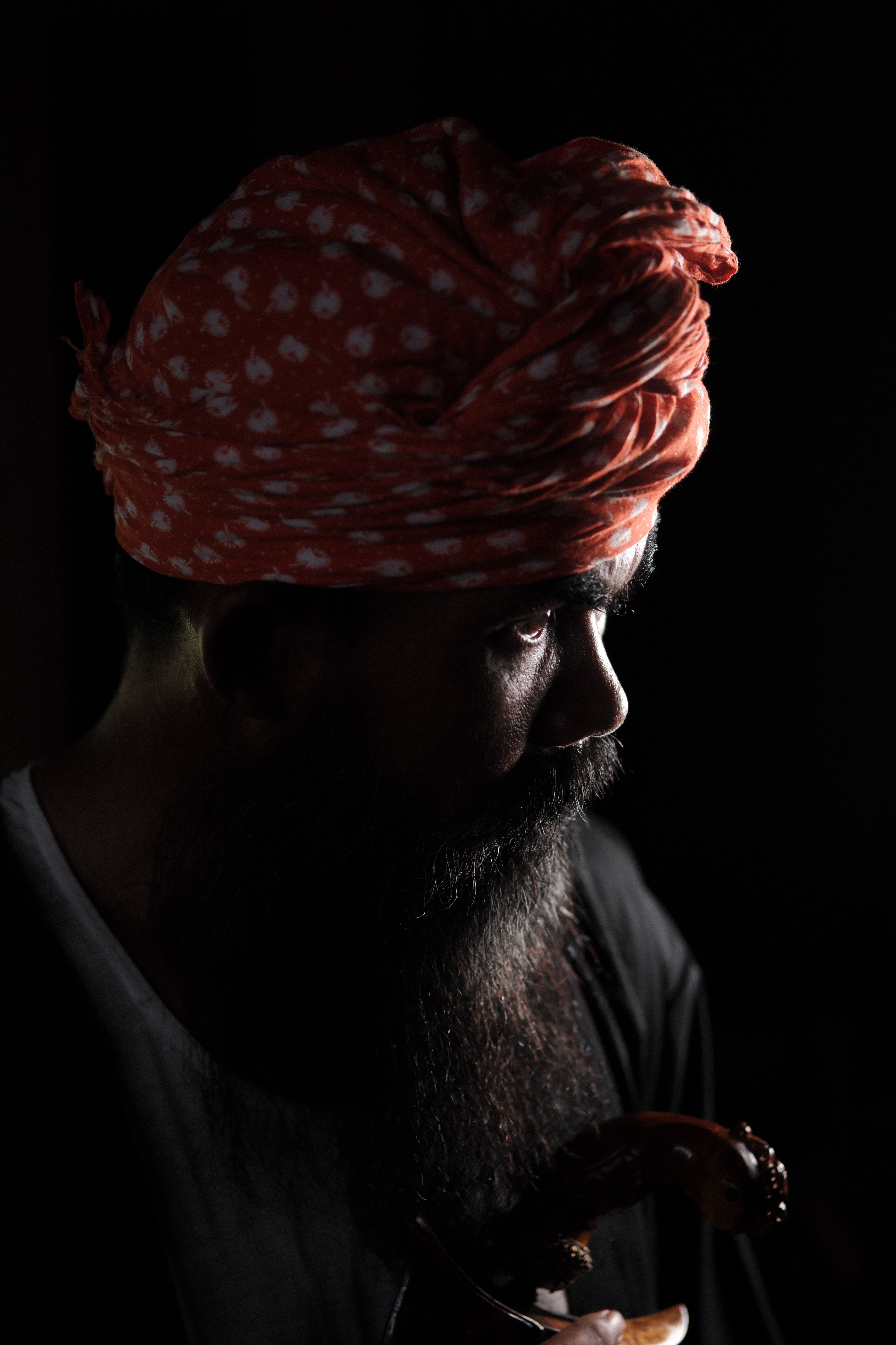 Dramatic portrait of a bearded man wearing a traditional turban, showcasing cultural attire.