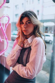 Stylish young woman poses indoors with neon lights reflecting urban vibes.