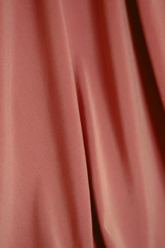 Close-up view of soft pink draped fabric showcasing its texture and details, perfect for backgrounds.