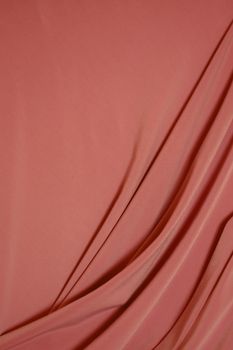 Close-up shot of soft peach velvet fabric elegantly draped, showcasing its texture and color.