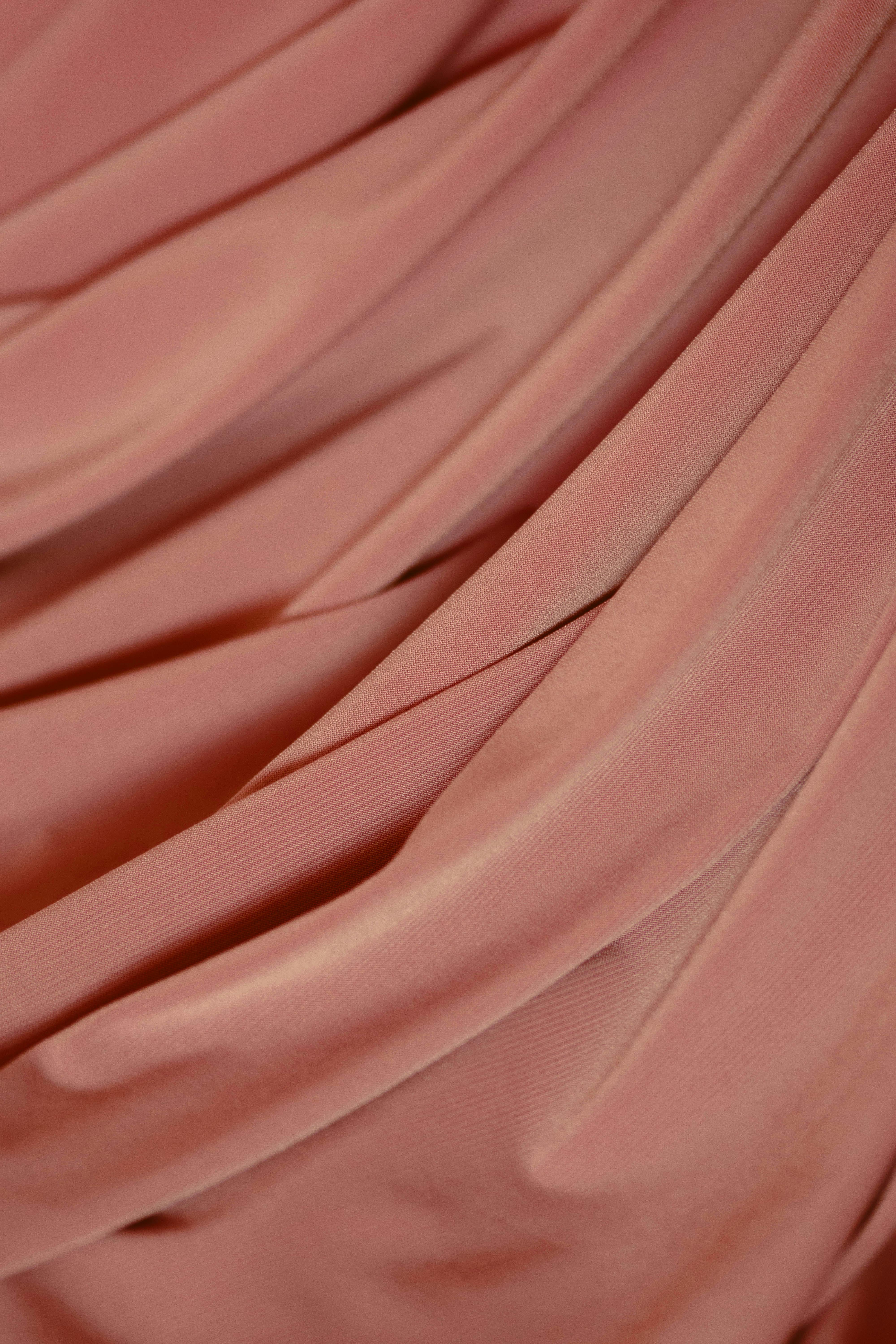 A soft and detailed view of flowing pink velvet fabric with elegant folds.