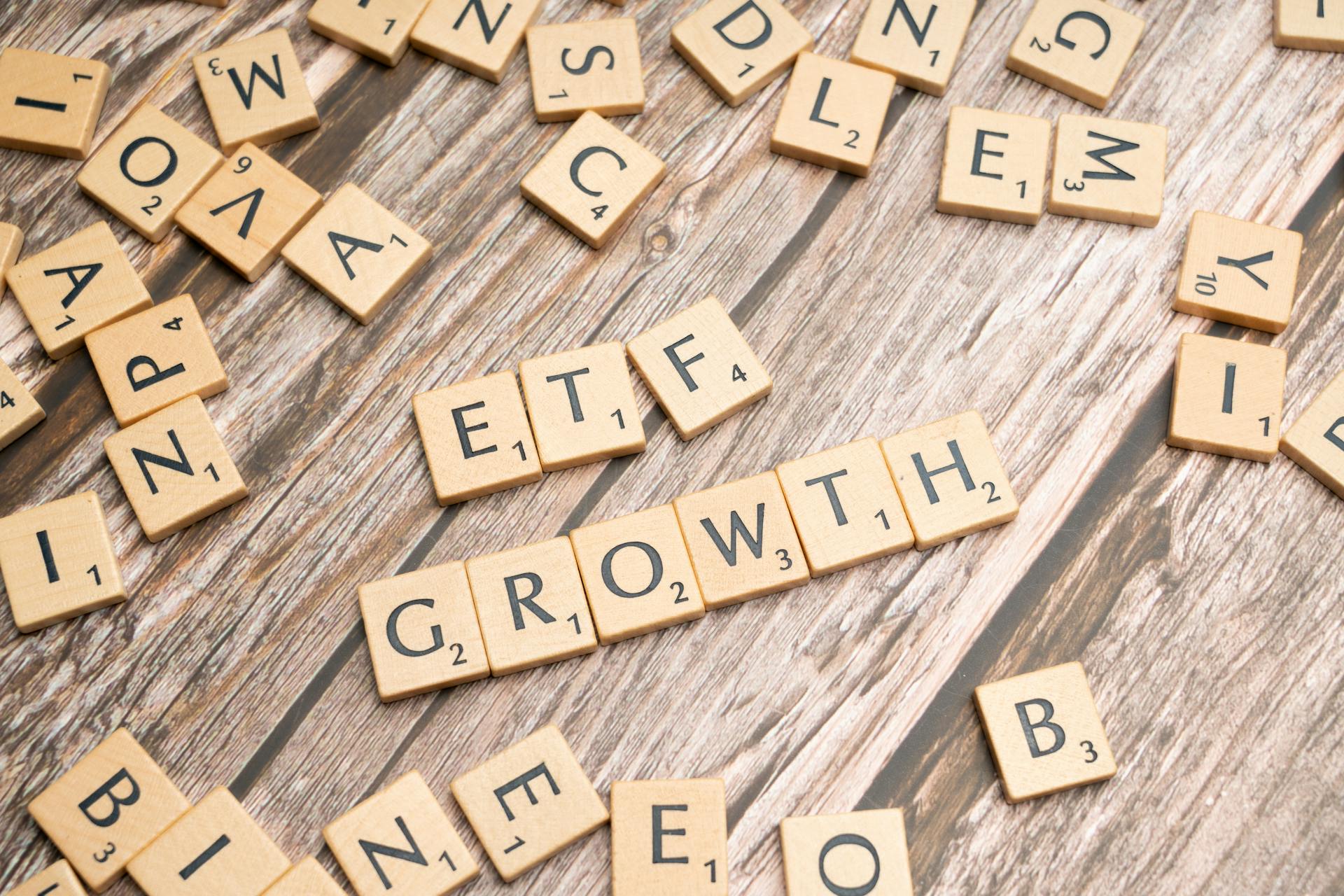 Wooden tiles spelling ETF growth on a wooden surface, symbolizing investment strategy.