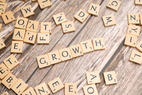 Free Scrabble tiles spelling 'growth' on a wooden surface symbolize progress and expansion. Stock Photo