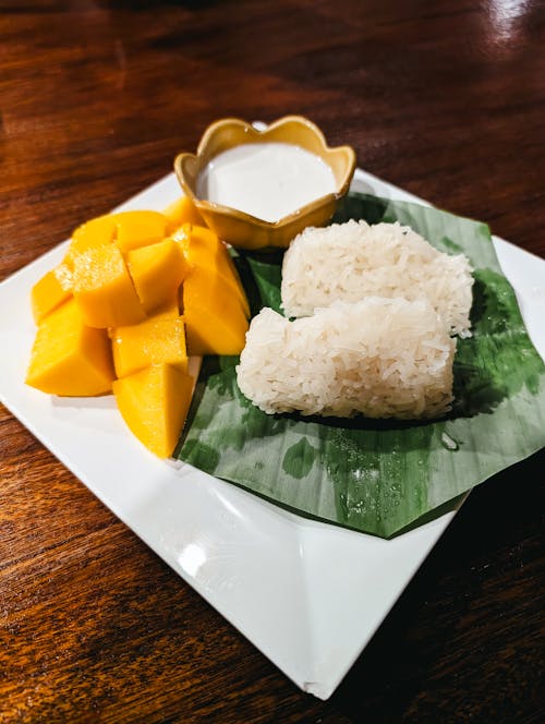 Mango and rice with dipping sauce on a white plate