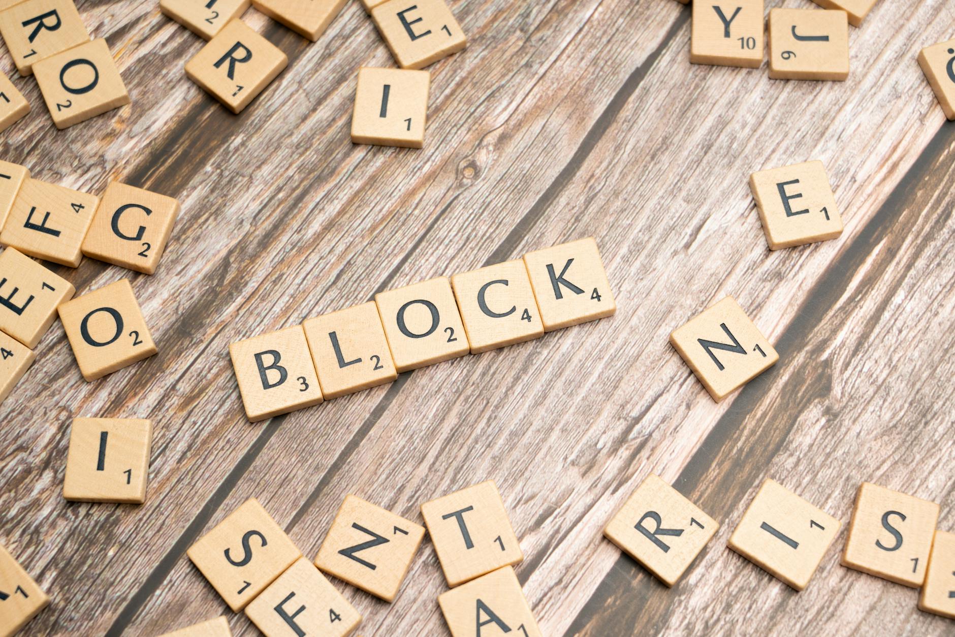 Scrabble tiles arranged to spell 'Block' on a textured wooden background.