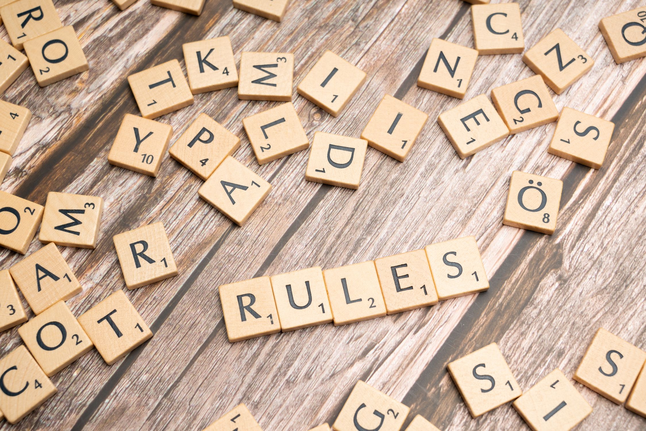 Allow Scrabble Scrabble letters spelling rules on a wooden table · Free Stock Photo