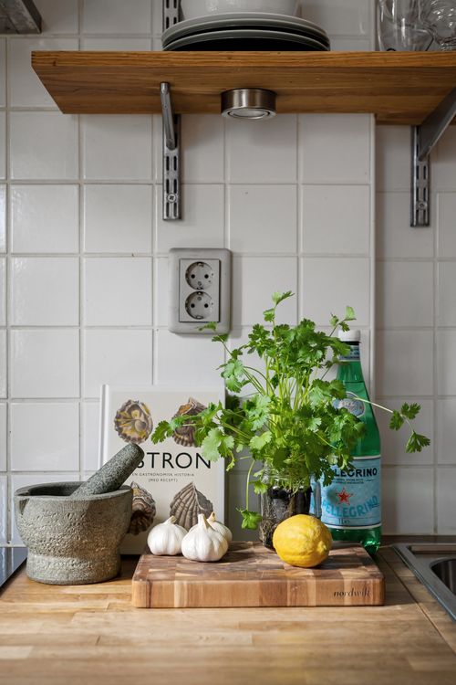 Free A bright kitchen corner featuring fresh herbs, garlic, and lemon on a wooden board. Stock Photo