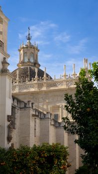 Seville Cathedral's stunning dome under a clear blue sky with orange trees in foreground.