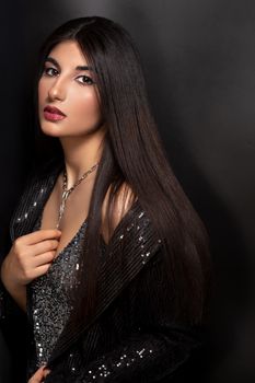 Elegant portrait of a brunette woman wearing a sparkling outfit and necklace, ideal for fashion and glamour themes.