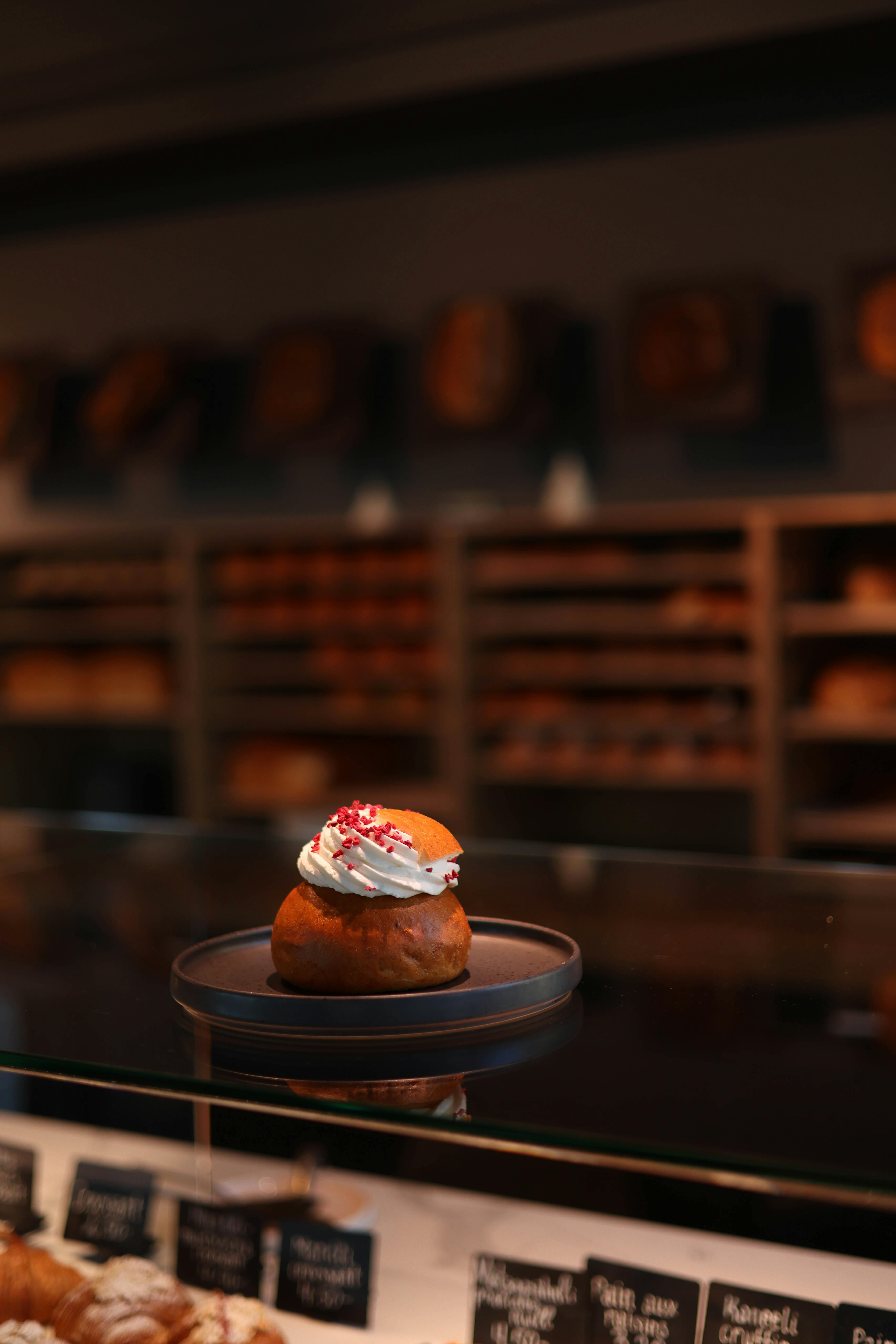 A tempting Swedish Semla pastry with whipped cream displayed in a bakery setting.