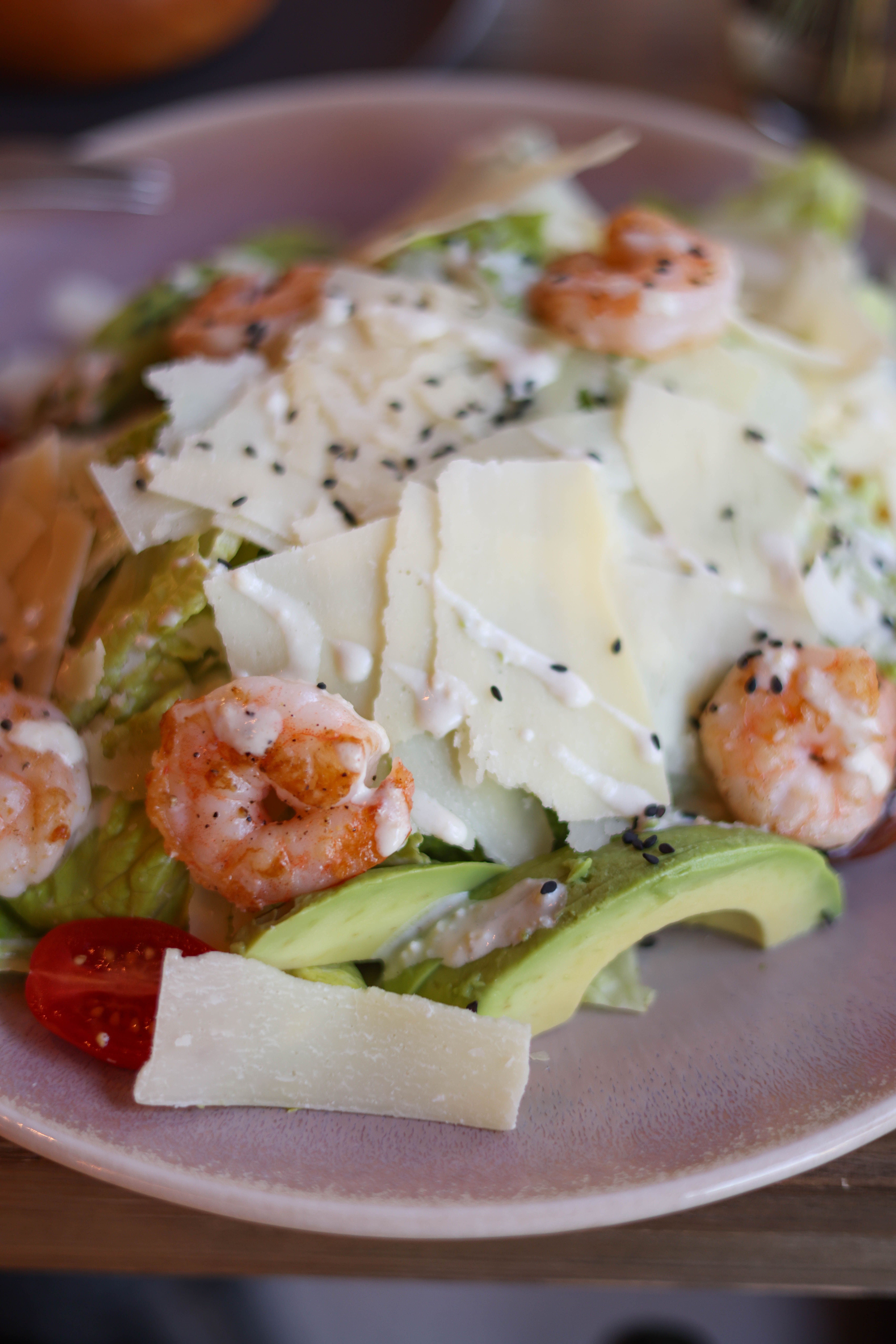 Delicious shrimp salad with avocado, cheese, and creamy dressing artfully presented on a plate.