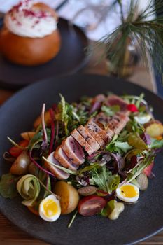 Delicious gourmet salad featuring seared tuna, quail eggs, potatoes, and fresh greens.