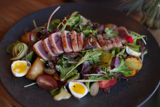 Sliced seared tuna over mixed greens with soft quail eggs, potatoes, tomatoes and cucumber