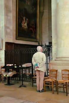 An elderly man admires a painting in a historic Parisian church, capturing a moment of quiet reflection.