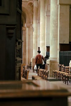 A lone person walks through a serene church interior in Paris, showcasing stunning architecture.