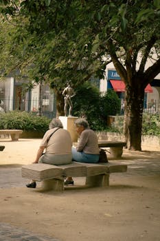 Two people relax on a bench in a Paris park, enjoying the art and scenery.