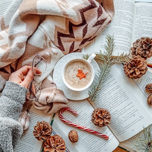 Free Warm and inviting winter setup with hot drink, open books, and festive decor for Christmas ambiance. Stock Photo
