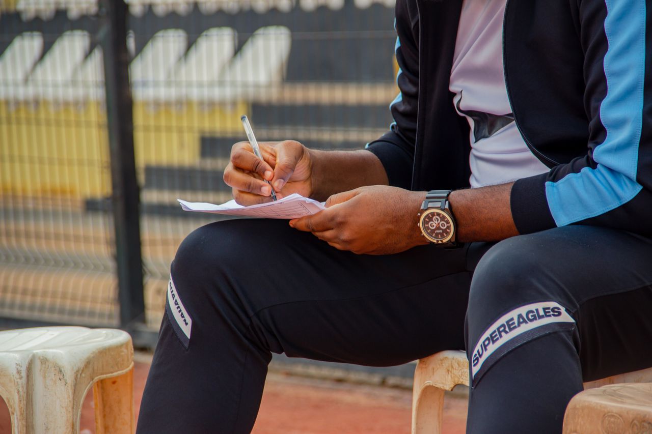 a coach writing notes on the sidelines during an outdoor sports match