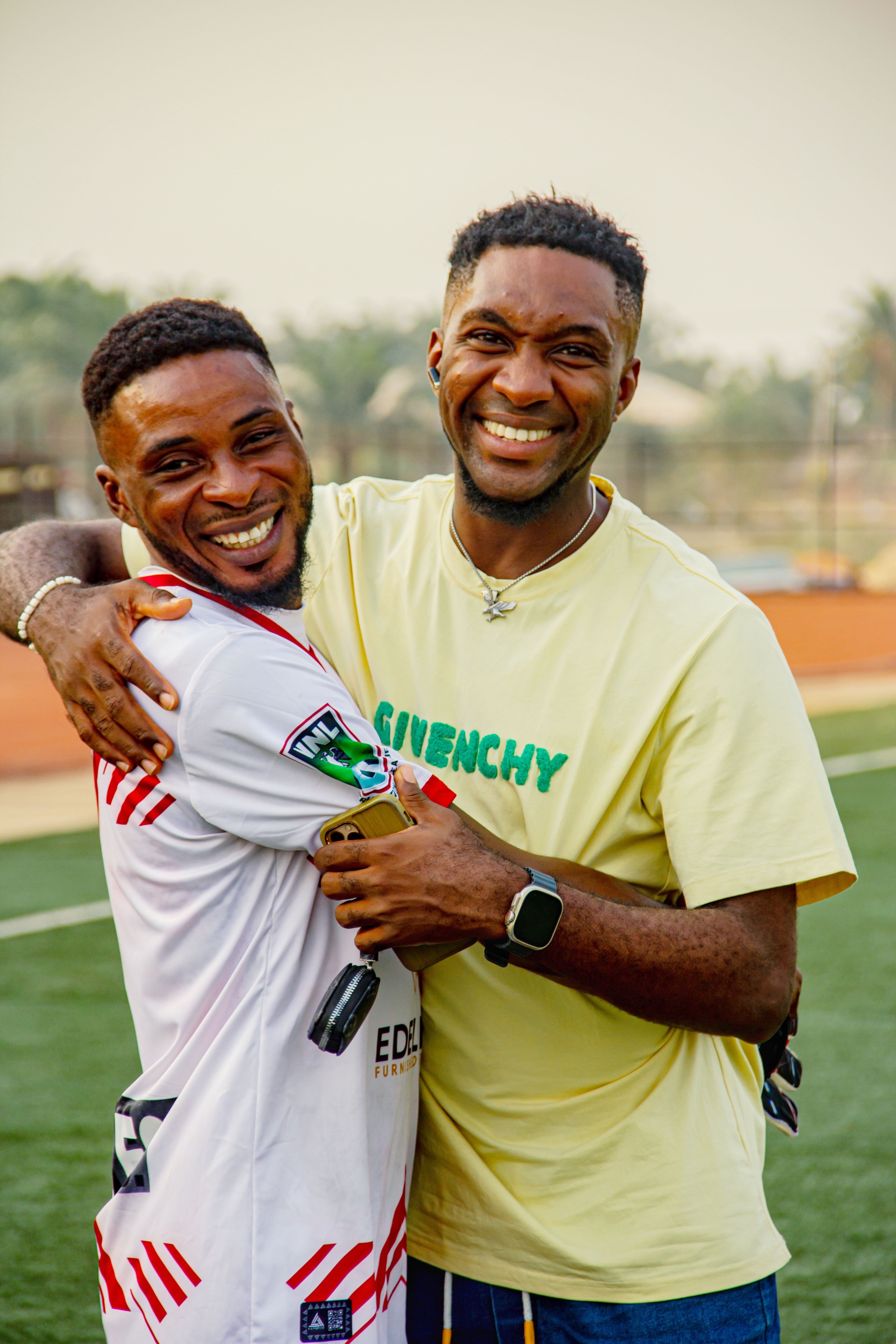 Two male friends embracing with happiness, wearing sportswear outdoors, showcasing friendship.