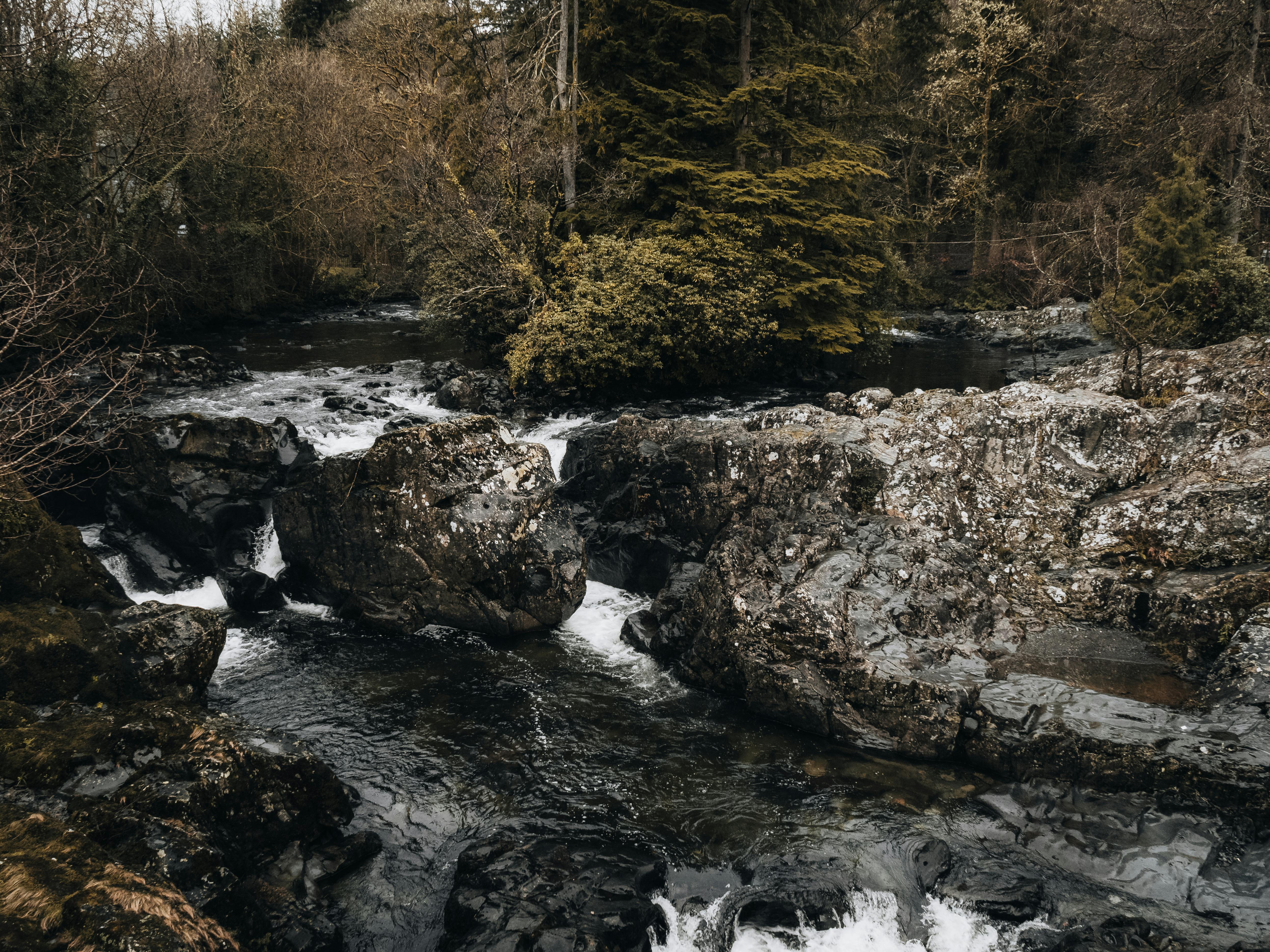 Tranquil view of a natural river flowing through rocky terrain in Betws-y-Coed, Wales.