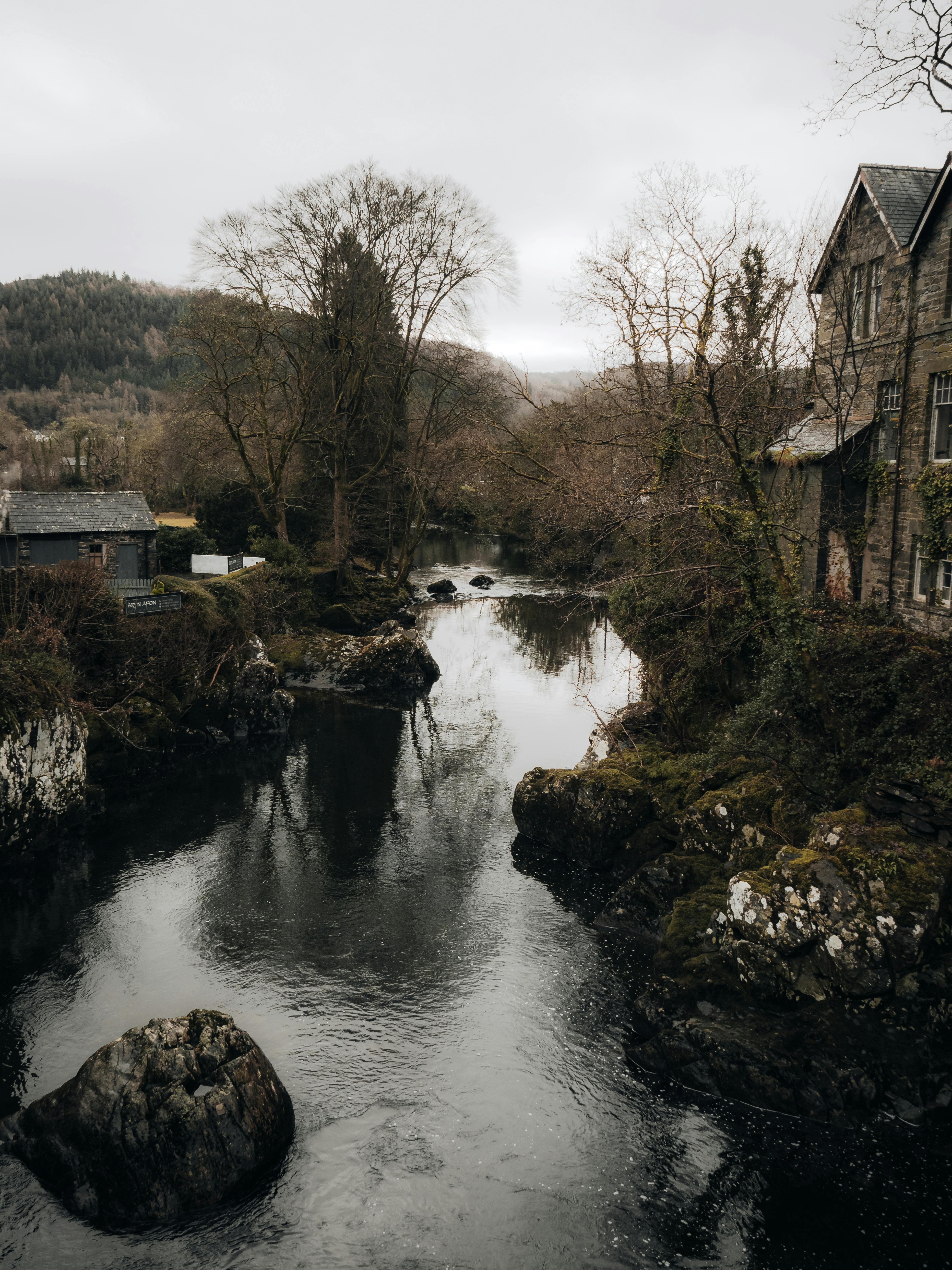 Scenic view of a river flowing through Betws-y-Coed, Wales, showcasing classic architecture and natural beauty.
