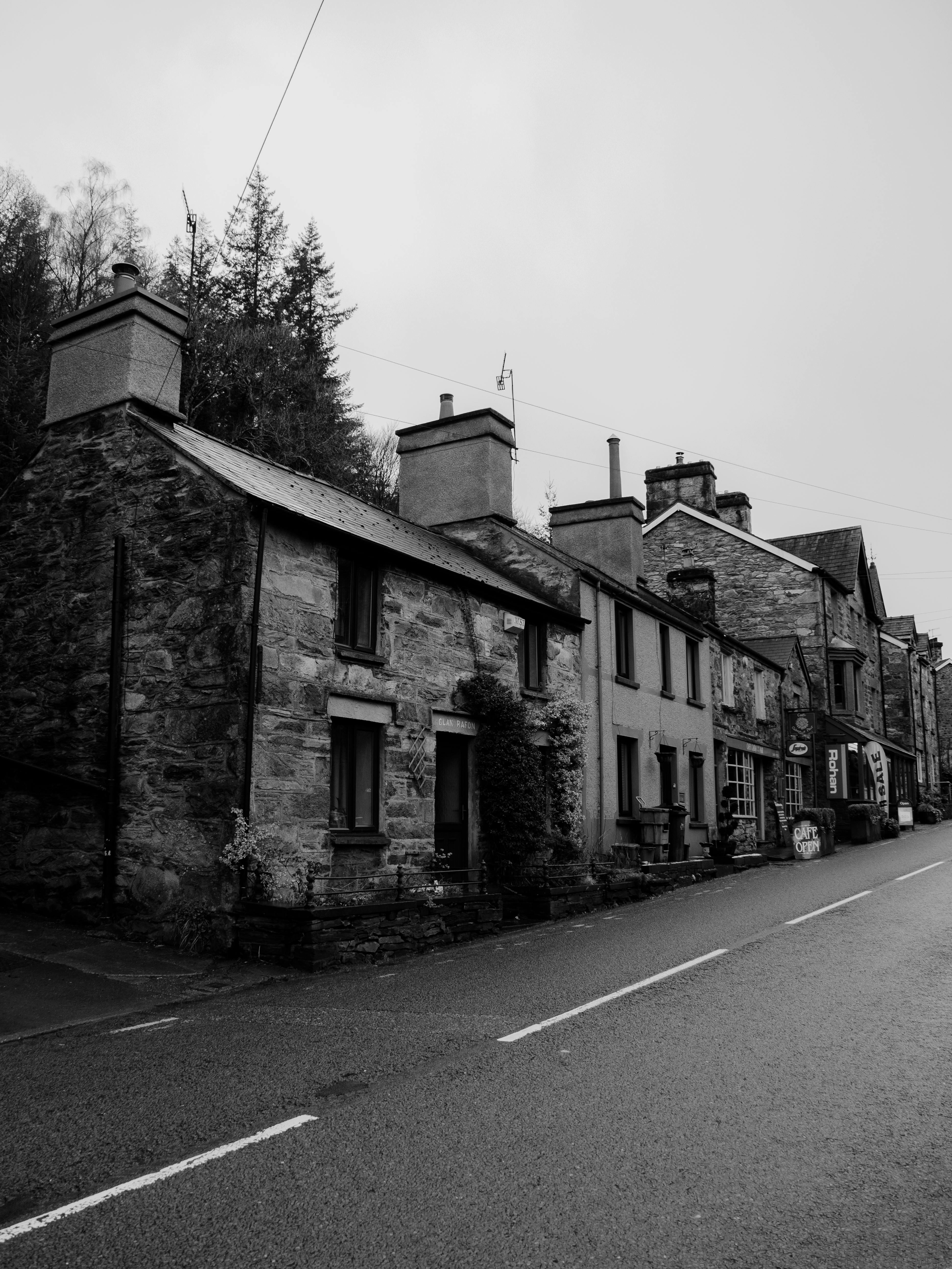 Black and white image of stone cottages on a quiet street in Betws-y-Coed, Wales.