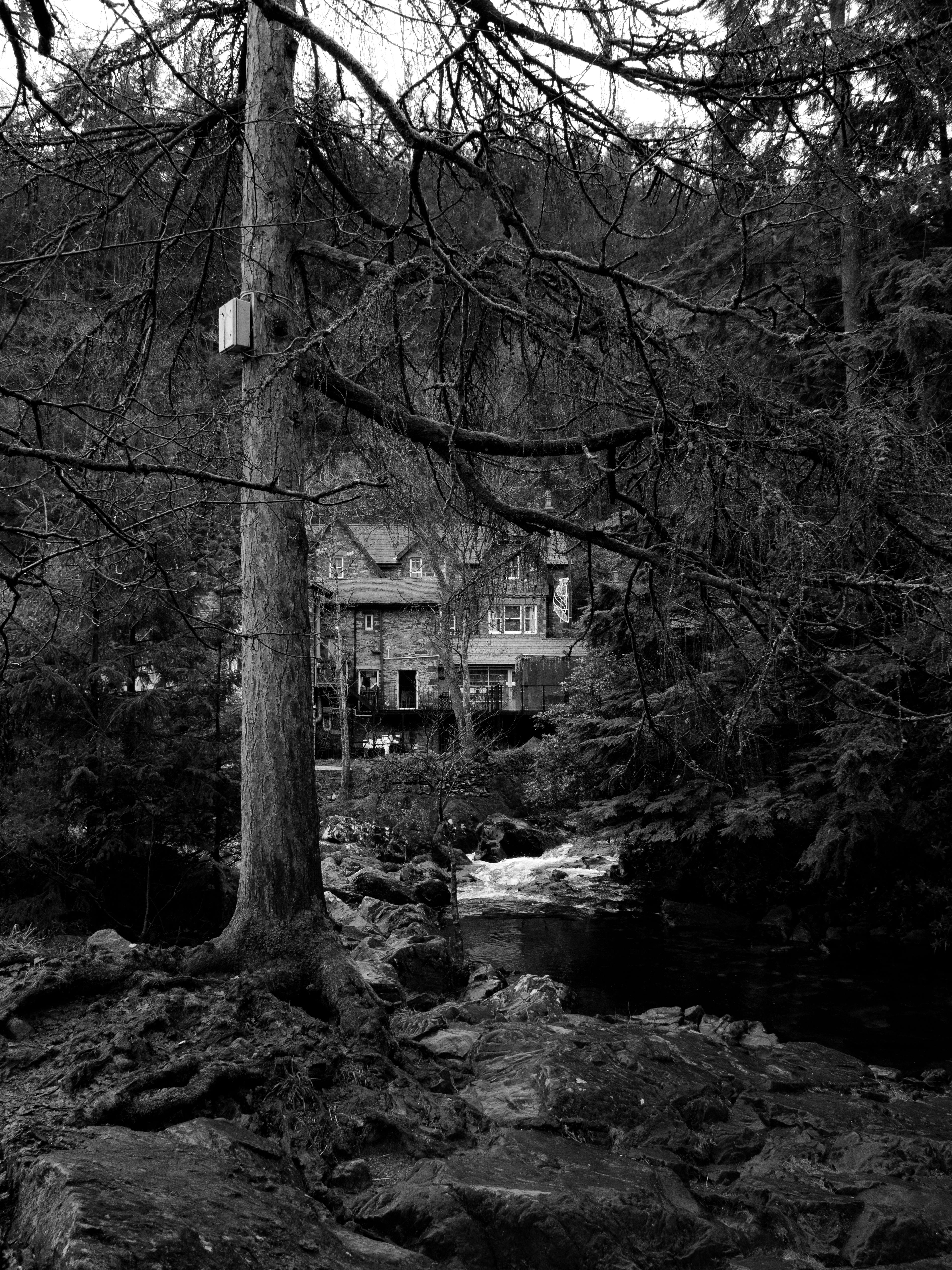 Black and white landscape of a historic house by a river in Betws-y-Coed, Wales.