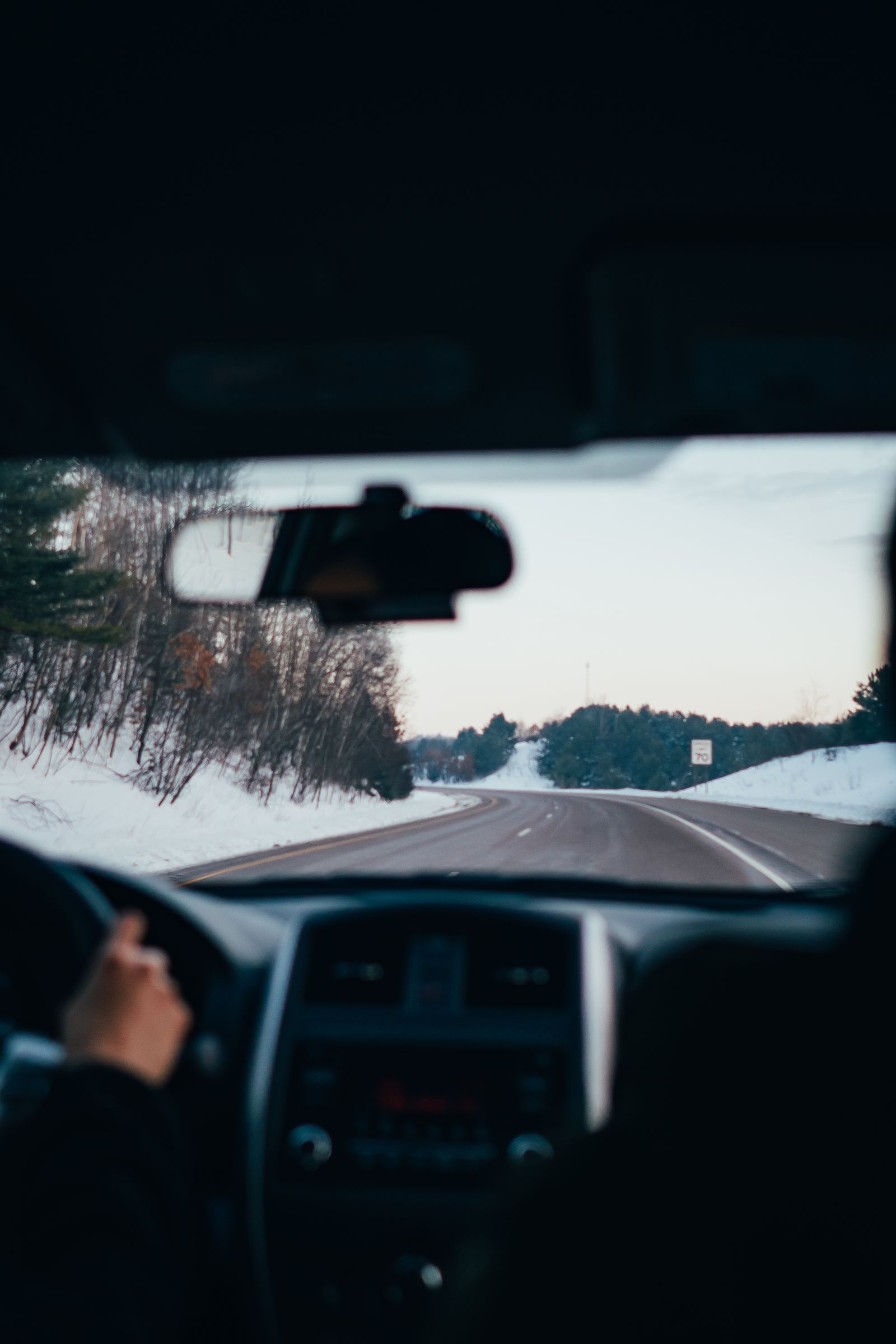 A snowy highway stretching into a calm winter landscape