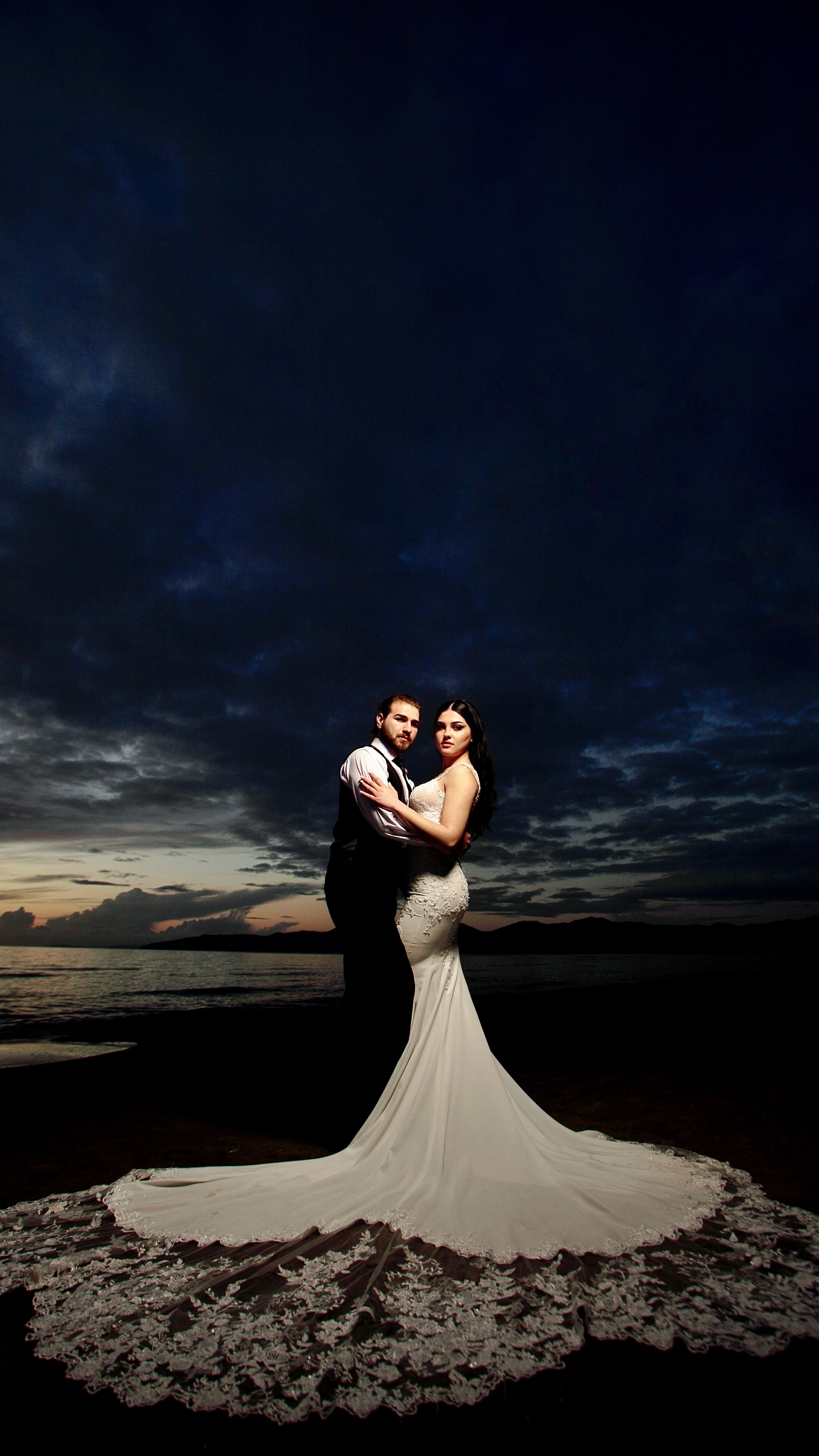 Elegant couple embracing on the beach at dusk, celebrating their wedding.